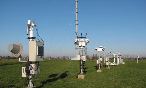 The BSRN station in Cabauw with in the background the 213 m tower. Central is the sun tracker with shadowed pyranometers (for diffuse irradiance), a pyrgeometer (downward longwave irradiance) and pyrheliometers (direct irradiance). Photo: Wouter Knap.