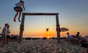 mensen schommelen op het strand bij zonsondergang in augustus 2024